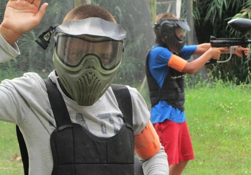 Jovens a fazer jogo de paintball com equipamento de segurança no campo de férias Páscoa