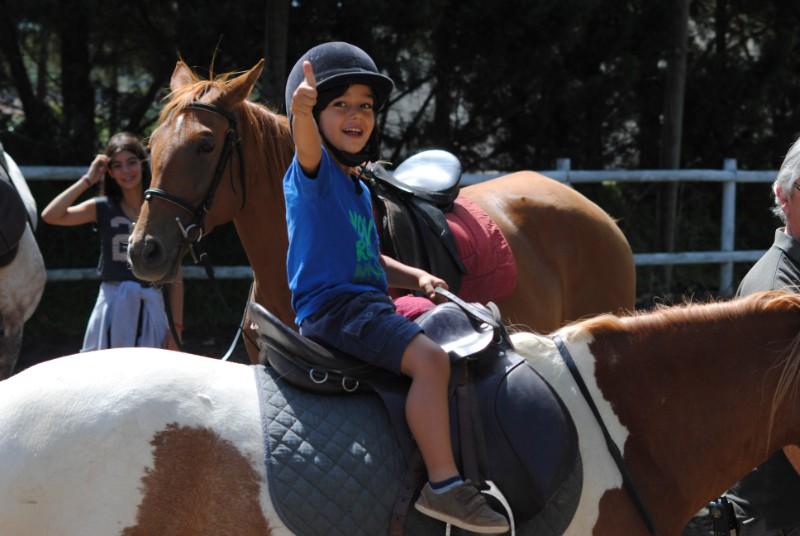 Criança a fazer um fixe enquanto anda de cavalo no campo de férias no Alentejo