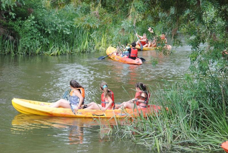 Crianças fazem atividade de canoagem no rio durante o campo de férias