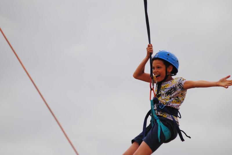 Menino feliz enquanto faz slide no campo de férias 
