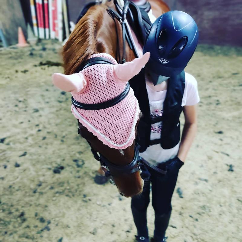 Criança equipada ao lado do cavalo no picadeiro do campo de férias equitação