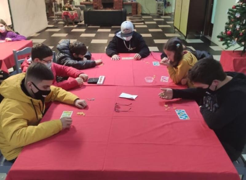 Crianças a fazer atividade de bingo na sala de lazer da colónia de férias de Inverno