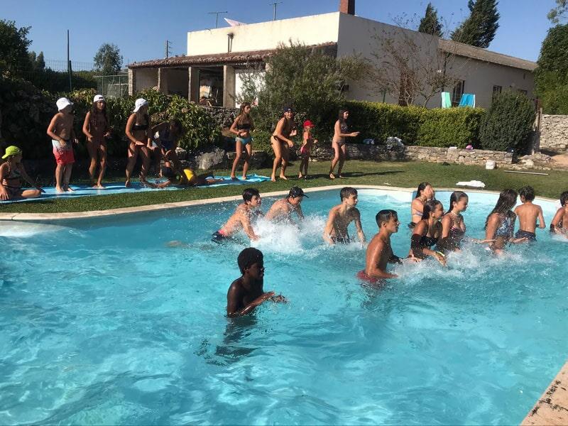 Crianças e jovens a fazer atividade aquática na piscina na colónia de férias