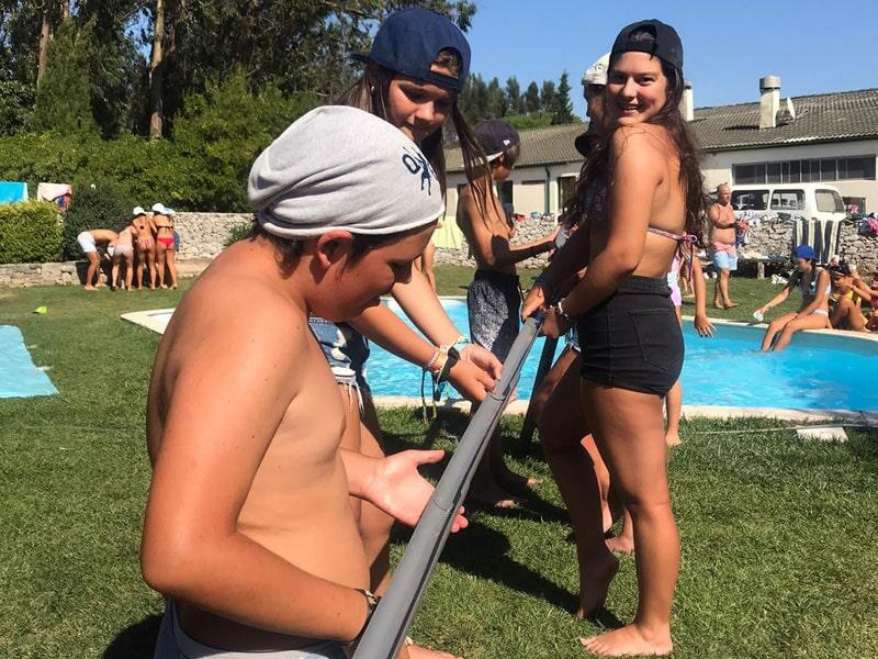 Crianças junto à piscina a fazer dinâmica de grupo no campo de férias Leiria