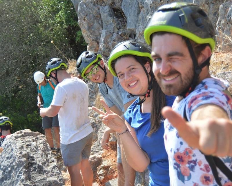 Jovens do campo de férias para aprender inglês durante atividade outdoor de escalada em rocha natural