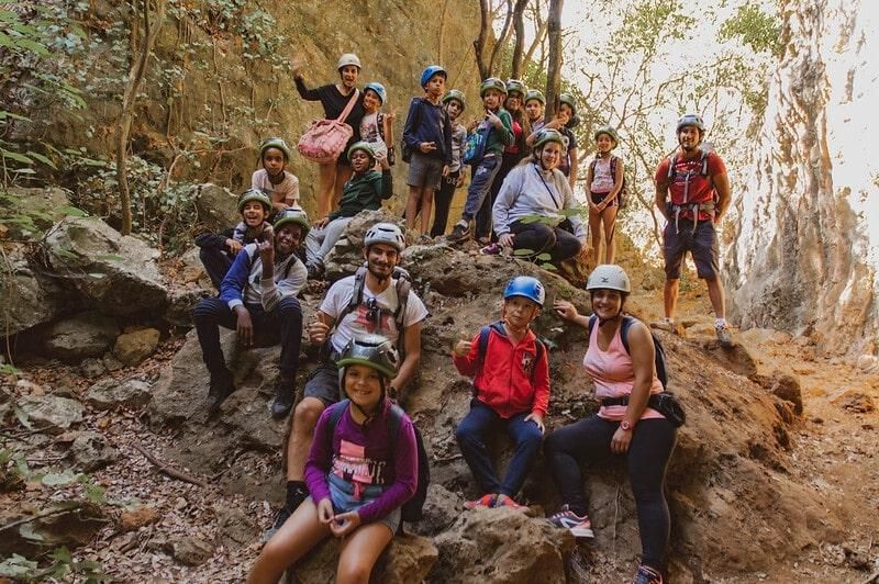 grupo de crianças alguns sentados outros de pé sobre uma rocha durante atividade de aventura no campo de férias Setúbal