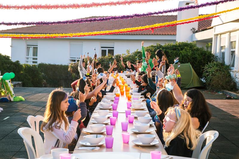 participantes sentadas à mesa, ao ar livre, para jantar no campo de férias Sintra