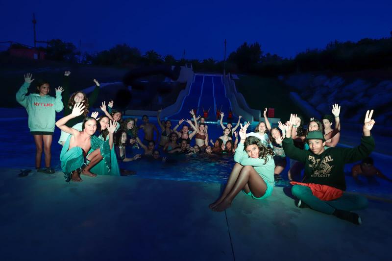 grupo de participantes dentro e fora da piscina durante a noite no campo de férias Lisboa