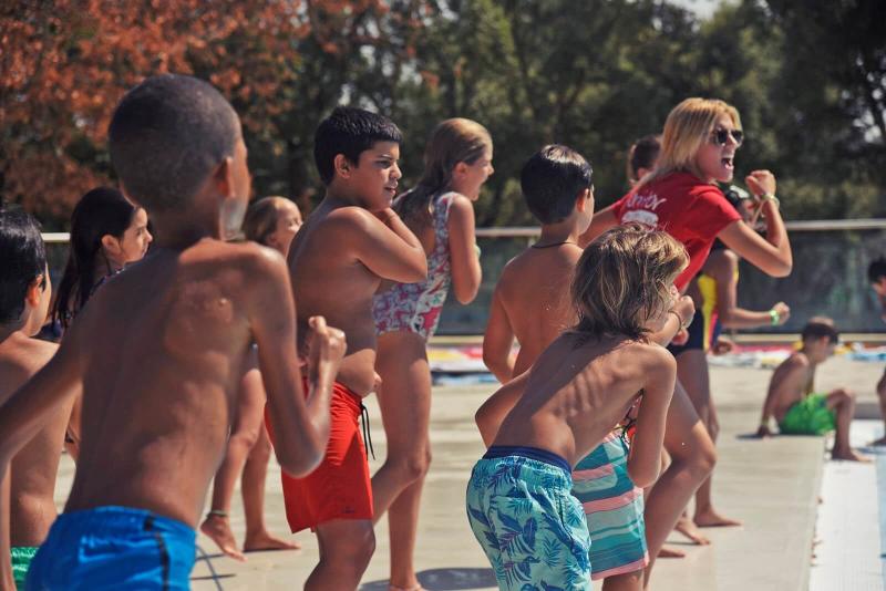 Crianças a fazer uma atividade de dança junto à piscina no campo de férias
