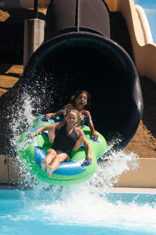 Meninas numa bóia dentro de um escorrega do parque aquático do campo de férias