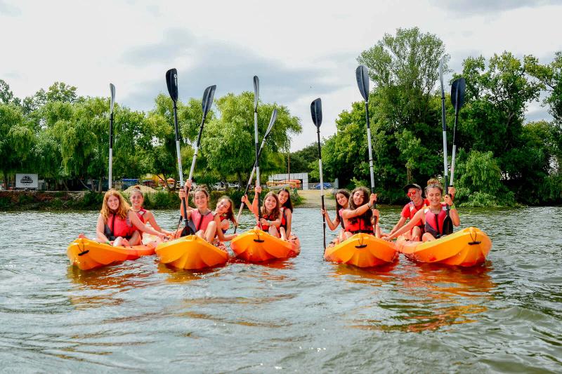 participantes com os remos levantados na atividade de canoagem do campo de férias