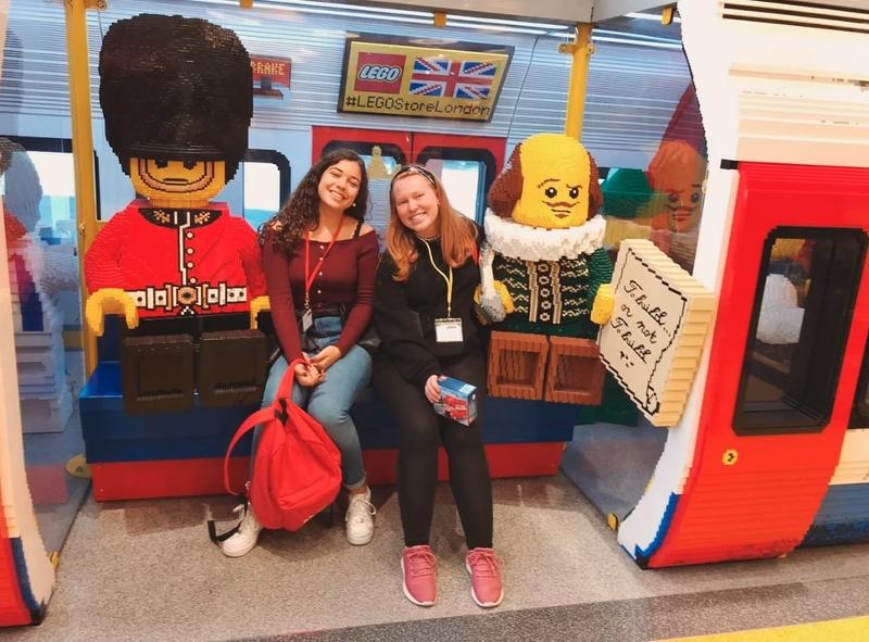 Jovens participantes no campo de férias Agosto sentadas no metro feito em lego na loja da LEGO em Londres