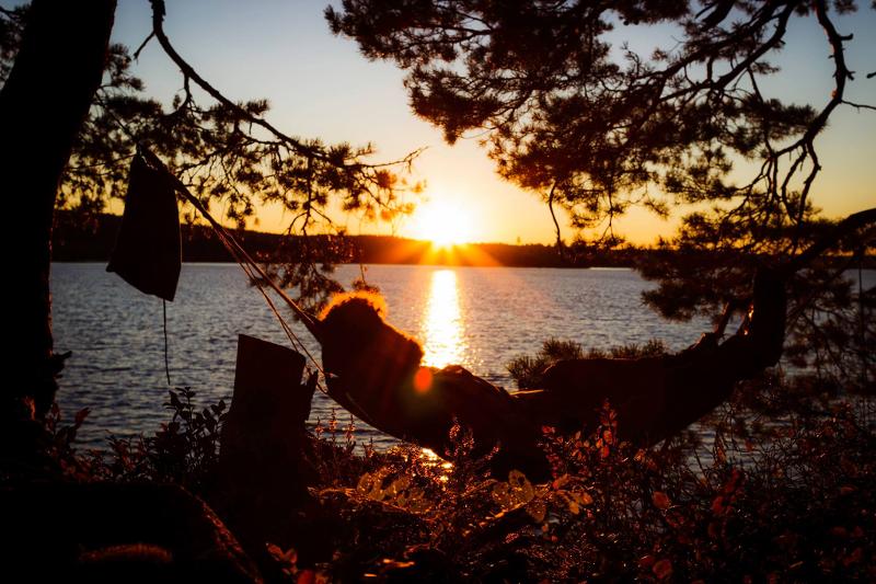 participantes à beira rio deitado num baloiço a ver o pôr do sol no campo de férias aventura
