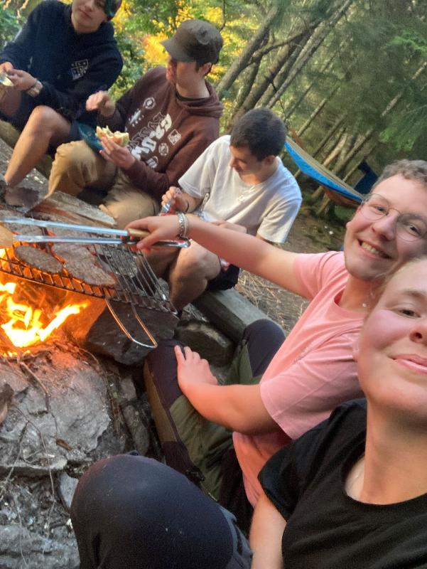 selfie de participantes a cozinhar hambúrgueres na fogueira no campo de férias
