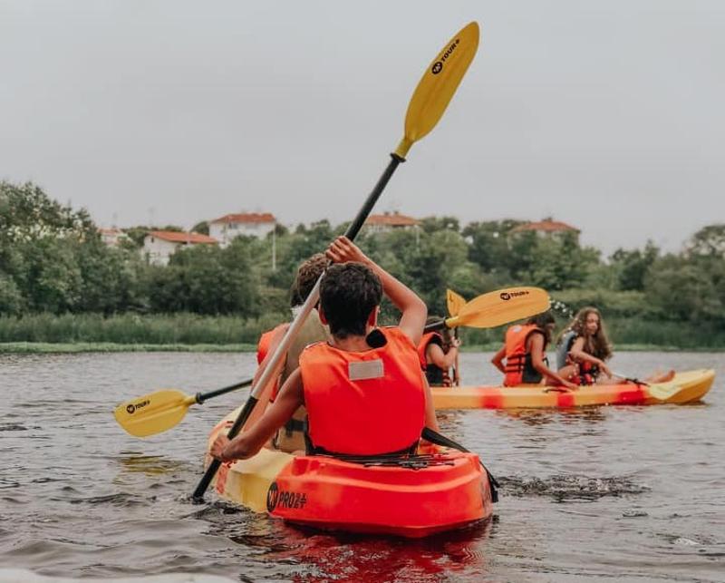 Grupo de crianças a fazer canoagem e a usar colete no campo de férias no Porto