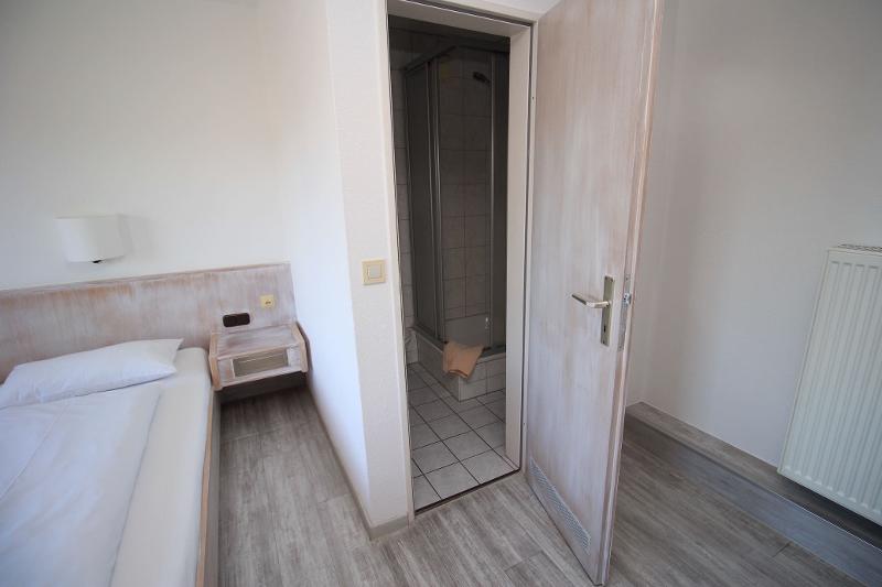 Um quarto simples e confortável, com cama e casa de banho privada, oferece um ambiente tranquilo para os participantes do curso de línguas.