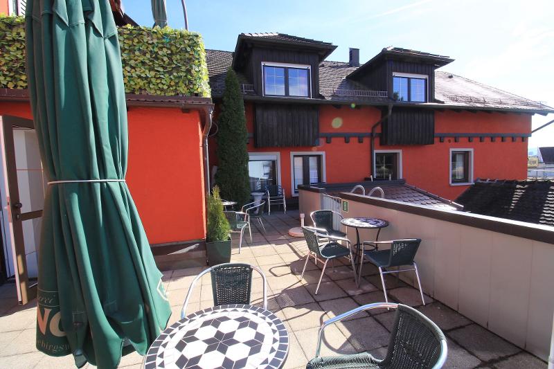 Um terraço ao ar livre com mesas e cadeiras, ideal para relaxar sob o sol, oferece um espaço agradável para pausas durante o curso de línguas.