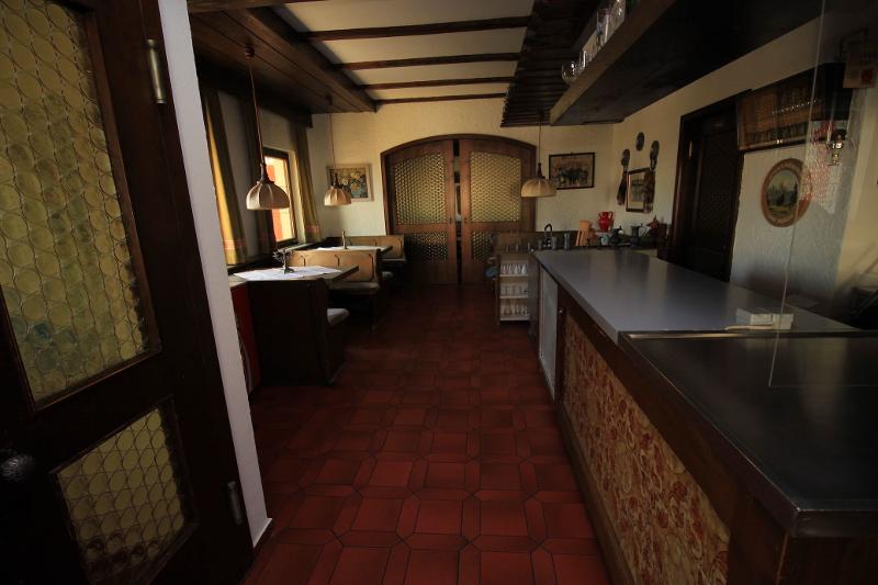 Uma sala de jantar rústica e acolhedora com mesas e bancos, decorada com um estilo tradicional, ideal para momentos de convivência durante o curso de línguas no estrangeiro.