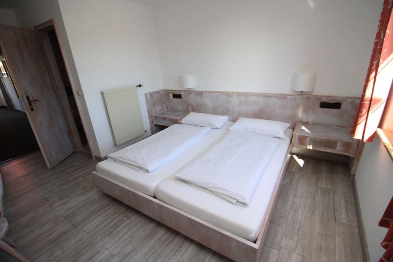 Quarto minimalista com cama dupla, decorado em tons claros, proporcionando um ambiente tranquilo e acolhedor para o curso de línguas estrangeiras.