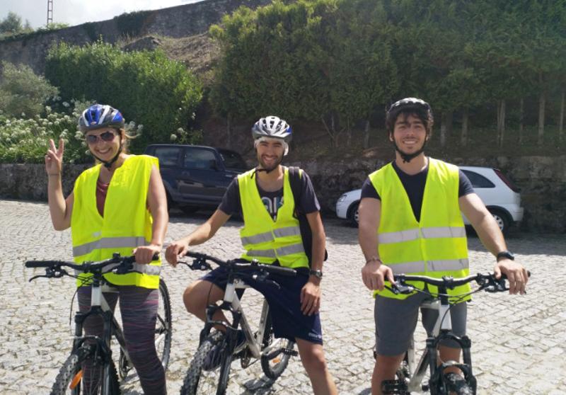 três jovens com bicicletas e coletes amarelos muito felizes