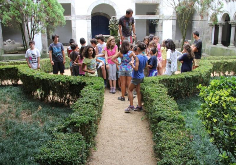 Várias crianças num jardim muito verde, a conversar e brincar