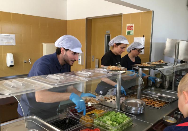 Três monitores na cantina a entregar comida aos participantes
