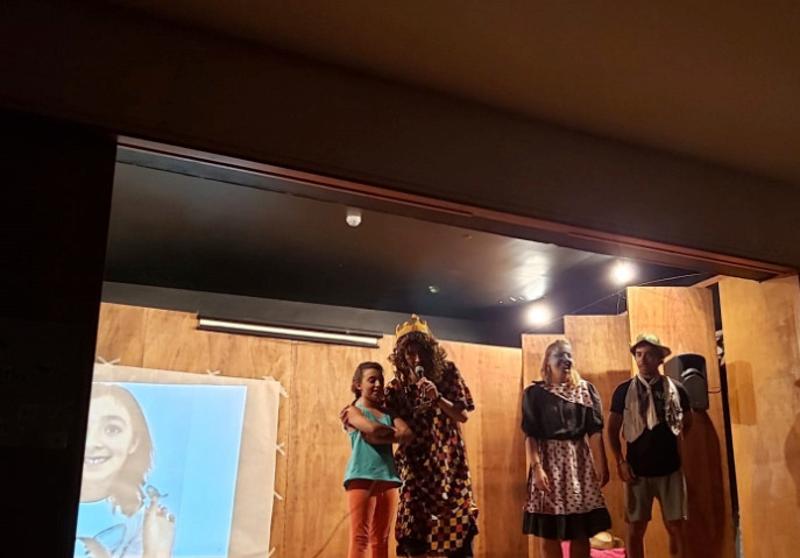 Uma menina e três monitores a fazer um teatro no palco