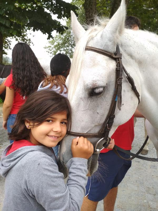 menina com a cara junta ao focinho do cavalo no surfcamp porto