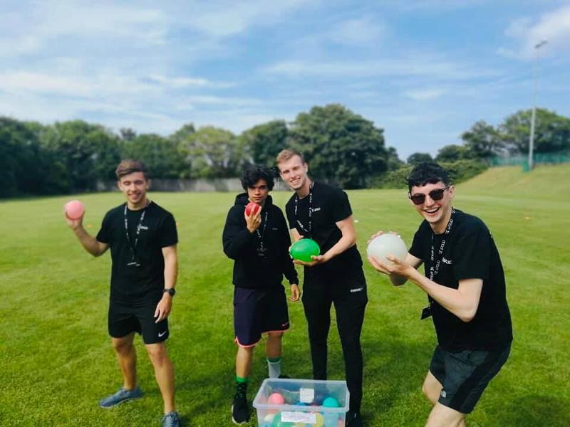 Jovens a jogar aos balões com água durante um curso de línguas no jardim