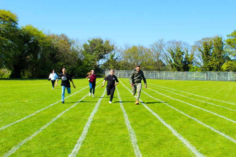 5 participantes a correr num campo de relvado no curso de línguas em Dublin