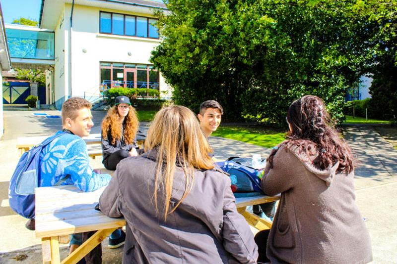 cinco participantes a conviver no espaço exterior da escola do curso de inglês em Dublin