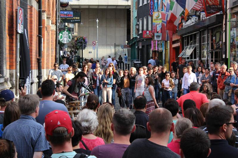 participantes a ouvir um artista de rua na excursão no curso de línguas em Dublin