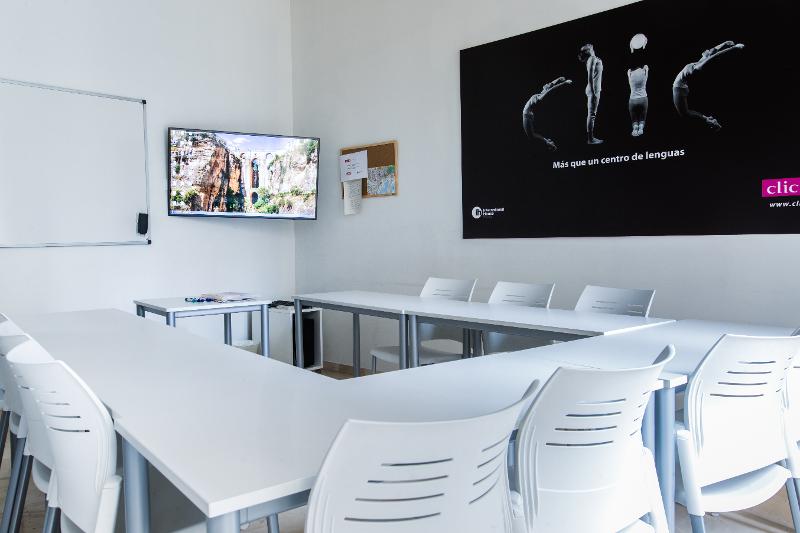 Sala de aula moderna e luminosa para um curso de espanhol com mesas brancas e equipamento audiovisual