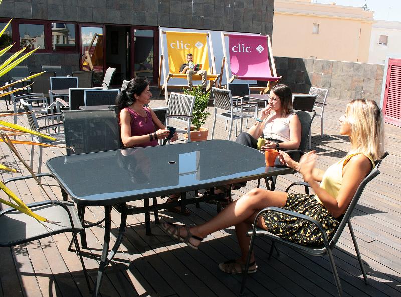 Alunas dos cursos de língua espanhola a conversar num terraço ensolarado e descontraído.