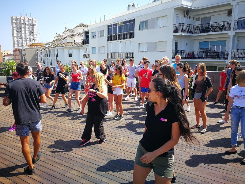 Grupo de estudantes dos cursos de espanhol a participar numa atividade de dança ao ar livre.