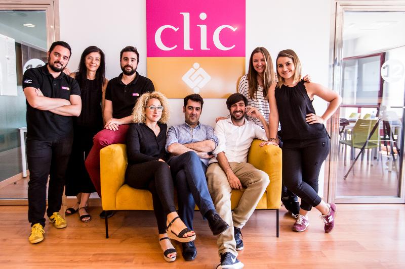 Equipa dos cursos de espanhol reunida em frente ao logotipo da escola, sorrindo para a foto.