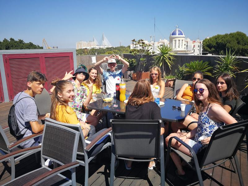 Grupo de alunos dos cursos de espanhol a conviver num terraço ensolarado.