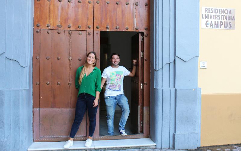 Dois alunos a sorrir na entrada de uma residência universitária, prontos para os cursos de línguas em Espanha.