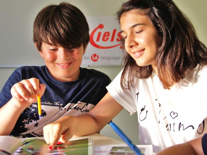 Dois alunos a sorrir enquanto estudam no caderno durante as aulas dos cursos de inglês em malta.