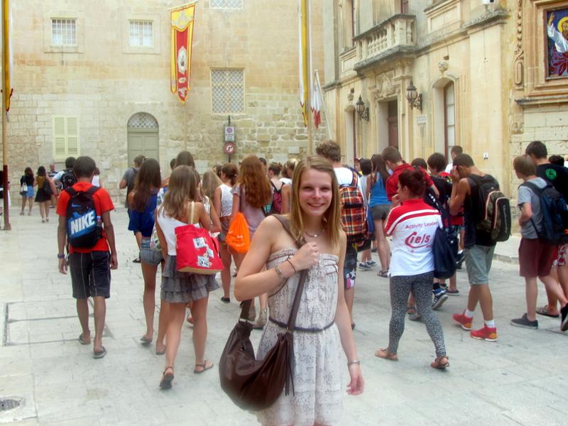 Rapariga feliz a caminhar pelas ruas de Malta, aproveitando o ambiente vibrante durante os cursos de inglês em malta.