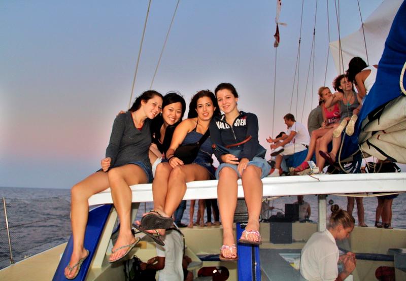 Raparigas sentadas num iate durante o pôr do sol, a desfrutar de um momento único após os cursos de inglês em malta.