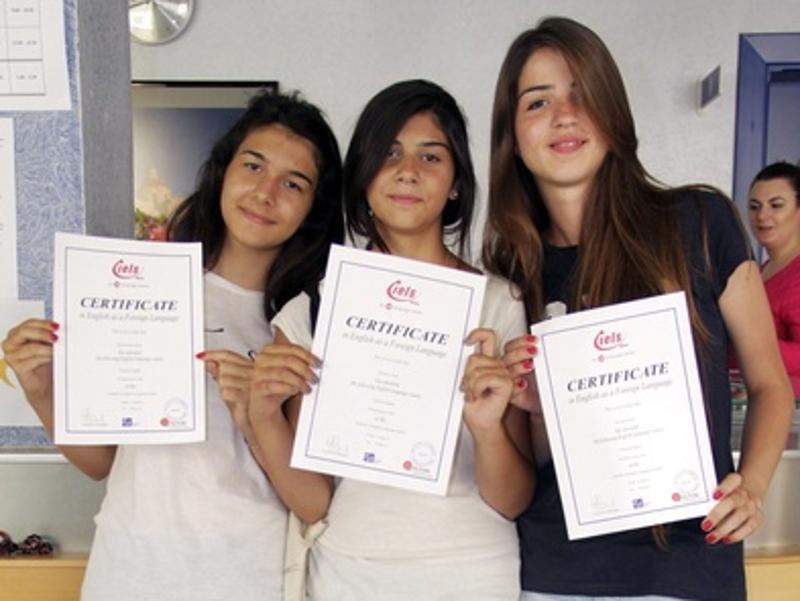 Três raparigas a segurar os certificados na mão, celebrando a conclusão dos cursos de inglês em malta.