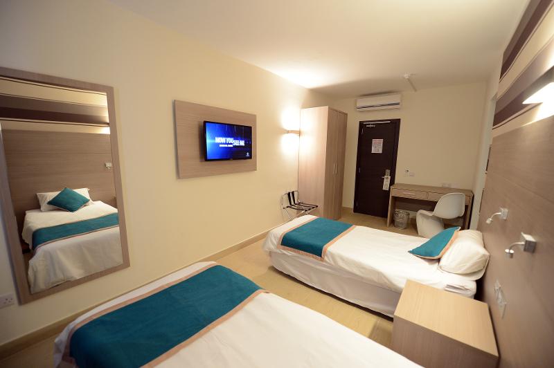 Quarto de 2 camas moderno no hotel, com TV, oferecendo conforto durante os cursos de inglês em malta.