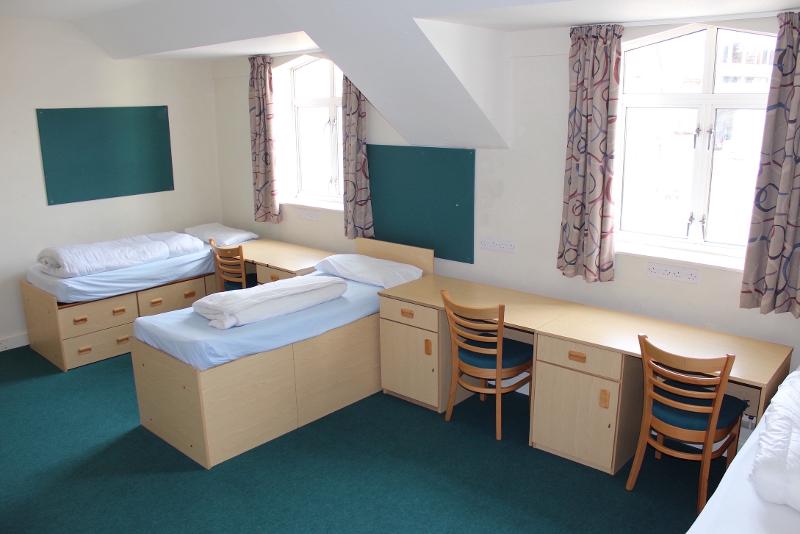 Quarto espaçoso com camas individuais e mesas de estudo, ideal para jovens que frequentam um curso de ingles para jovens.
