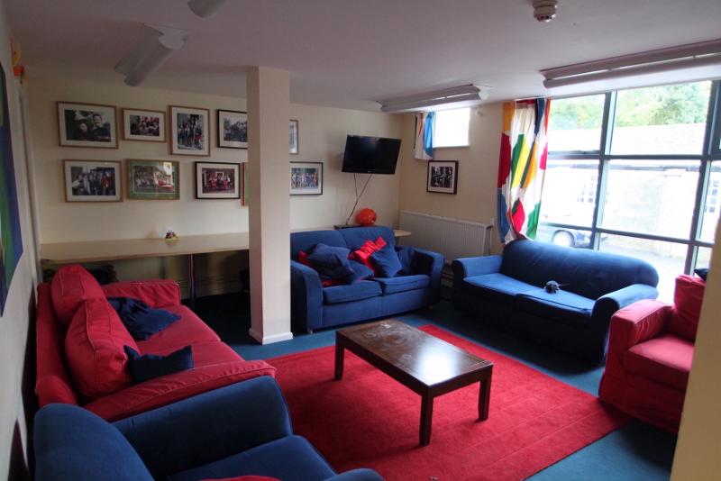 Sala de convívio acolhedora com sofás e televisão, ideal para relaxar e interação num curso de ingles para jovens.