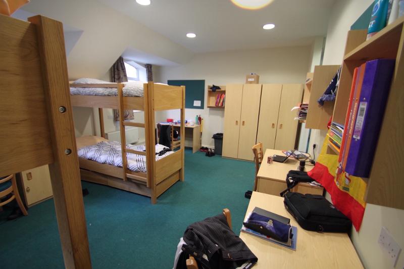 Quarto espaçoso com beliches e mesas de estudo, proporcionando um ambiente confortável para participantes de um curso de ingles para jovens.