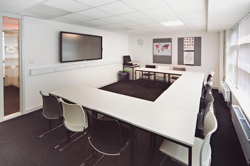 Sala de aula moderna com mesas em formato U para aulas interativas no curso de ingles para jovens.