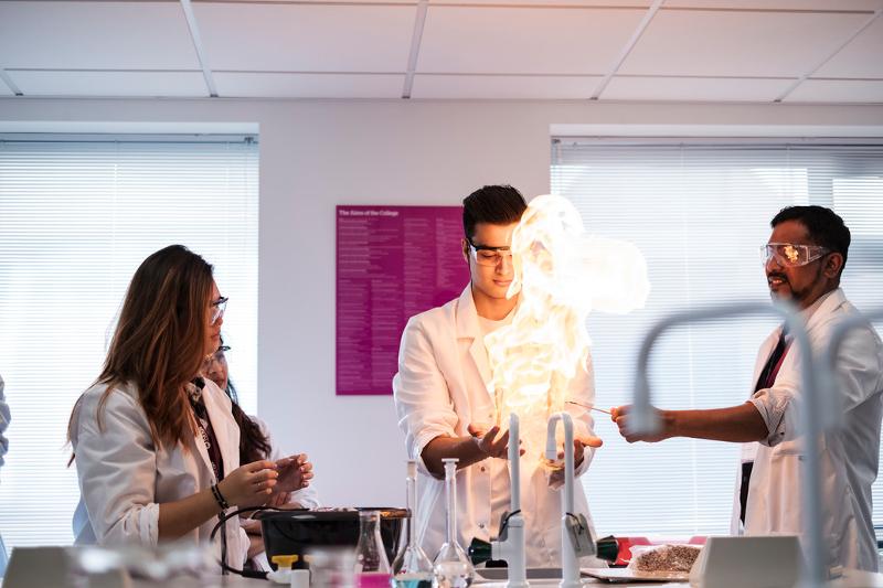 Alunos em um laboratório de ciências durante uma demonstração prática, observando uma reação química num curso de ingles para jovens.