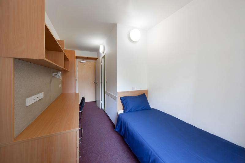 Quarto compacto com cama individual e espaço de estudo, perfeito para estudantes de curso de ingles para jovens.