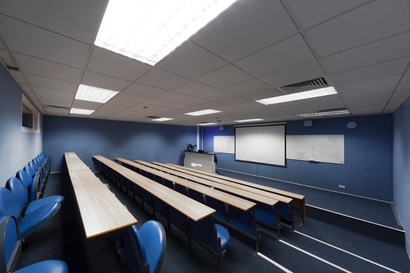 Sala de aula moderna com cadeiras dispostas em anfiteatro, projetada para sessões interativas de curso de ingles para jovens.